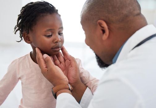 Medical doctor checking a girl throat with care in his office at a modern surgery center. Man pediatrician touching the patients neck during healthcare, medicare and illness consultation at clinic