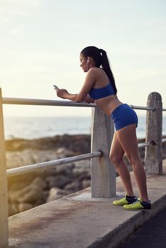 Status update Another amazing morning run. a fit young woman using her phone and earphones during a workout outdoors.
