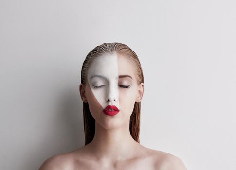 Dont be afraid of being different. a beautiful woman wearing face paint and red lipstick against a plain background.