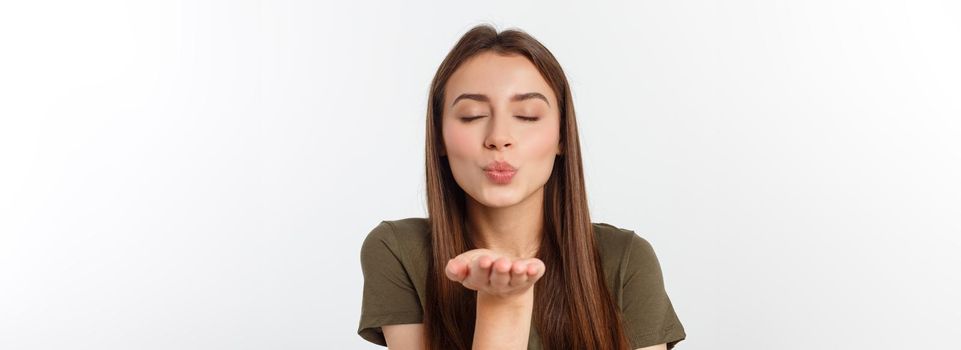Portrait of a young woman blowing a kiss isolated over white.