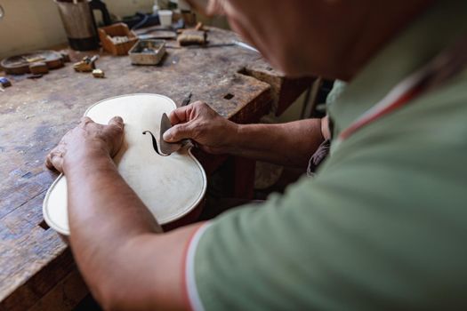 luthier carving and sculpting the f holes a violin with a knife