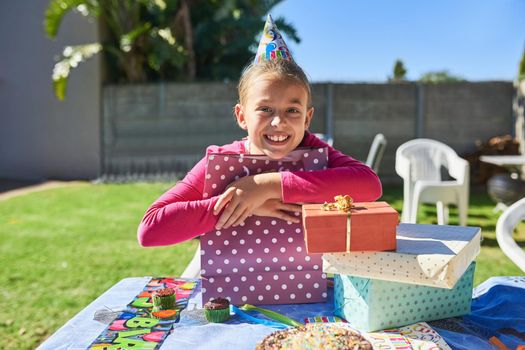 So many presents and theyre all for me. Portrait of a happy little girl enjoying her birthday party outdoors.