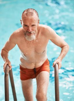 Swimming is super slimming. a happy senior man exercising in a swimming pool at a gym.