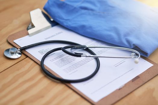 Diagnostic essentials. Closeup shot of a stethoscope lying on a doctors clipboard with a folded hospital gown.