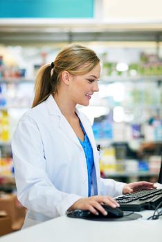 Sending an email confirmation for her customers prescription. a young pharmacist using a computer at the checkout counter.