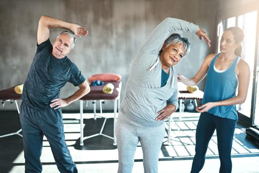 Activate a healthy retirement and join the gym. a senior man and woman working out with the help of an instructor.
