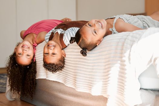 Fun, playful and silly kids lying on a bed with cute hairstyle and smiling portrait. Little siblings relaxing, playing indoors showing growth, child development and childhood innocence