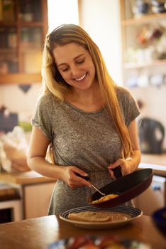 Serving up a plateful of deliciousness. an attractive young woman cooking at home.