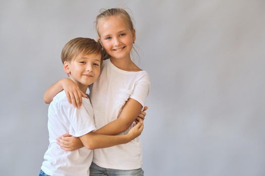 Cute two kids, little boy and girl in white t-shirts on gray background