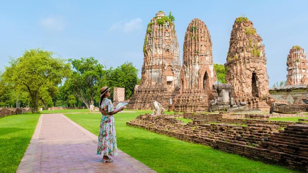 Ayutthaya, Thailand at Wat Mahathat, women with a hat and tourist map visiting Ayyuthaya Thailand