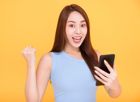 Excited young woman holding mobile phone and celebrating success