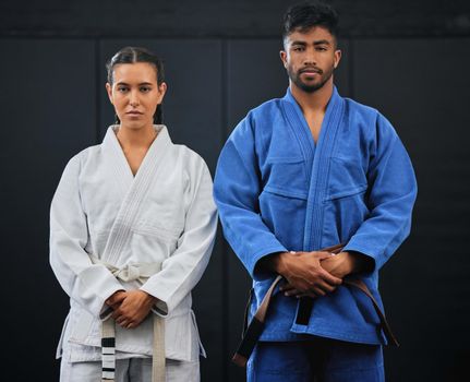 .Fitness, motivation and discipline karate training with a student and teacher standing proud in a center or dojo. Young woman learning defense, strength and endurance lesson from martial arts coach.