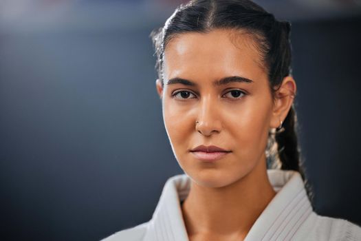 Portrait of female athlete, serious, and in karate gear staring ahead. A young girl, healthy, with a determined and motivated face at martial arts training. Discipline, fight and fitness in the dojo.