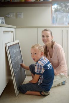 Well get these chores done together. Portrait of a mother and son writing chores on a chalkboard.