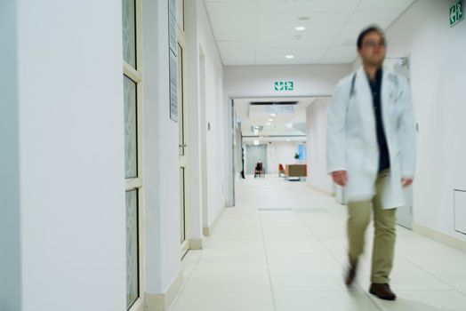 Doing his hospital rounds. a doctor walking in the corridor of a hospital.