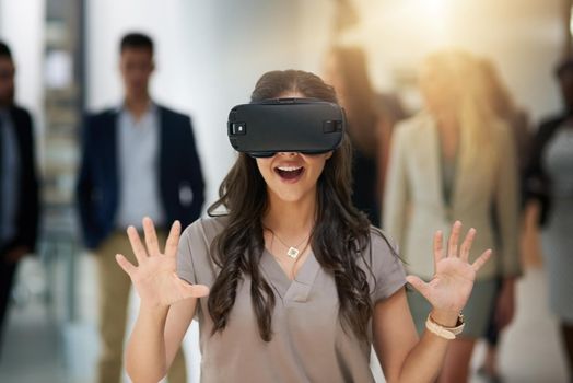 Technology sure is amazing. a young businesswoman wearing a VR headset in a busy office.