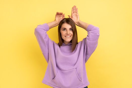 Woman showing bunny ears gesture and looking playful happy, childish behavior.