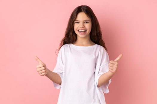 Smiling little girl showing thumbs up, like gesture looking at camera demonstrating her satisfaction