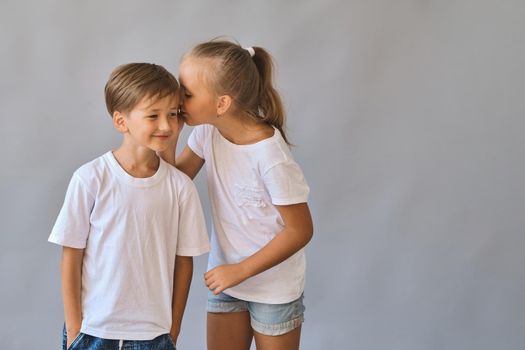 Cute two kids, little boy and girl in white t-shirts on gray background