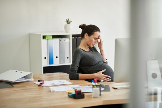 Today was exhausting. a pregnant businesswoman in discomfort in her office.