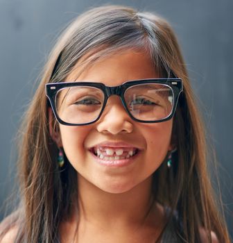 The joys of being a kid. Studio portrait of a little girl wearing spectacles against a dark background.