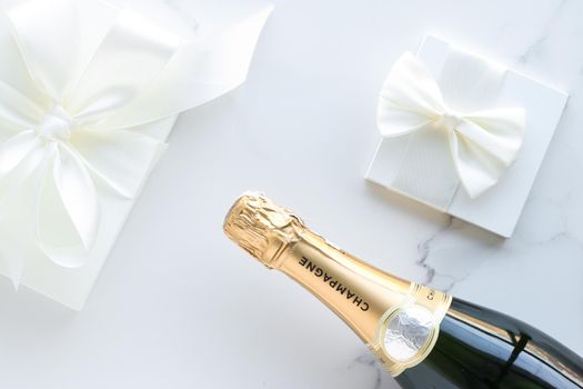 A champagne bottle and a gift box on marble