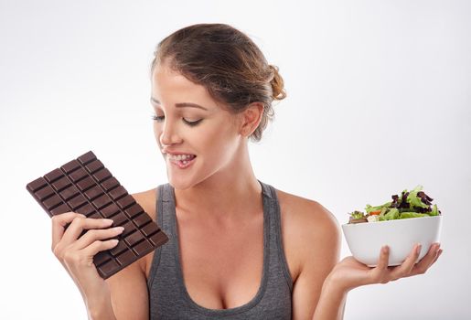 Shes a lover of chocolate. Studio shot of an attractive young woman being tempted by something sweet.