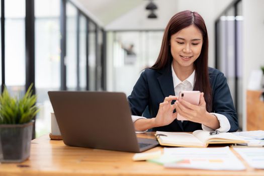 Business asian woman using mobile phone during checking an email or social media on internet. accounting financial concept.