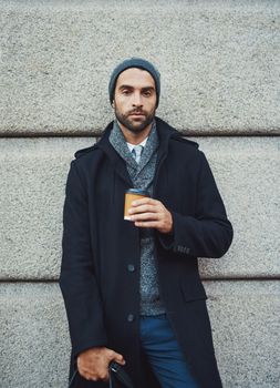 Be a coffee drinking individual... espresso yourself. a fashionable young man leaning against a building in an urban setting.