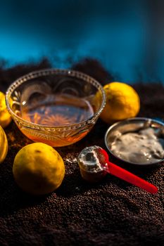 Mustard seed face mask for glowing skin on black surface with raw fresh lemons, mustard seeds, yogurt, honey, and cornflour.