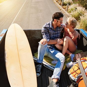 Adventure is worthwhile. a young couple relaxing on the back of a pickup truck while on a road trip.