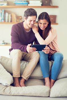 Relaxing in their wireless home. a smiling young couple using a digital tablet while relaxing on the sofa at home.