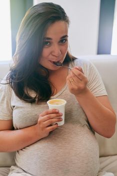 Everything just taste better when youre pregnant. Portrait of a pregnant woman eating yoghurt.