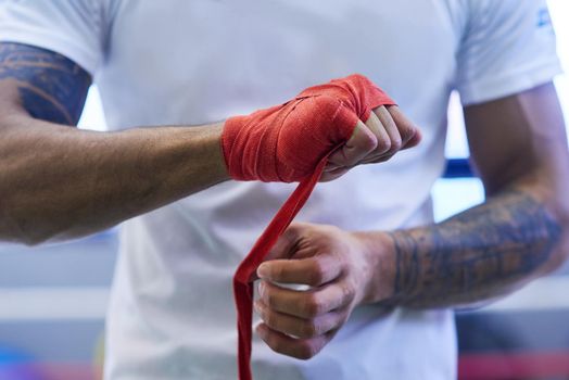 Lendinging strength to your hand during the punch. an unrecognizable man strapping his hands and wrists in he boxing gym.