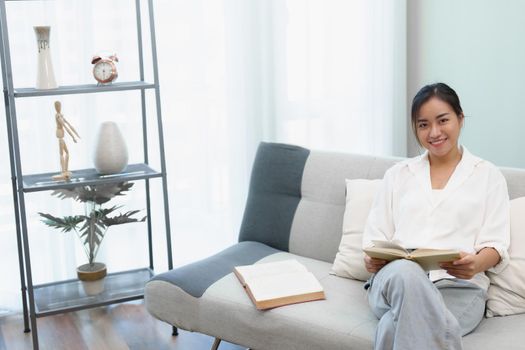 Hobby of a woman sitting on the sofa reading a book to relax.
