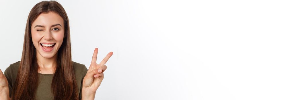 Young woman showing two fingers, positive or peace gesture, on white.