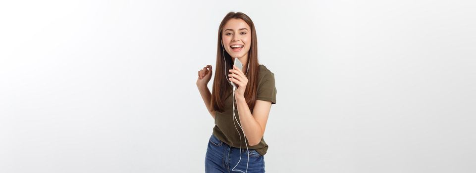 Portrait of a cheerful cute woman listening music in headphones and dancing isolated on a white background.