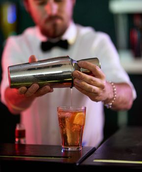Adding a kick to it. a barman mixing drinks in a nightclub.