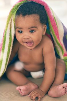 Sweet bundle of joy. an adorable baby girl covered in a colorful blanket at home.