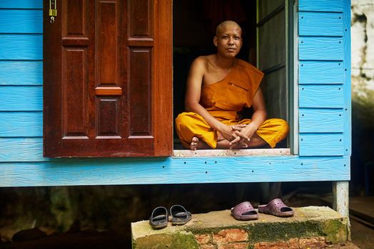 Rule your mind or it will rule you. Portrait of a buddhist monk sitting in the doorway of his home.