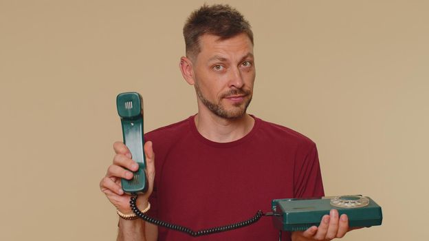 Handsome man in red t-shirt talking on wired vintage telephone of 80s says hey you call me back