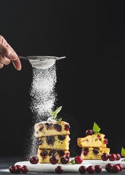 Baked sponge cake with cherries sprinkled with powdered sugar