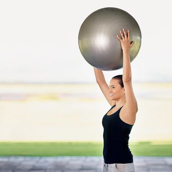 Raising the stakes. a young woman working out with an exercise ball.