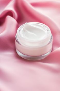 Luxury face cream jar on a soft pink silk