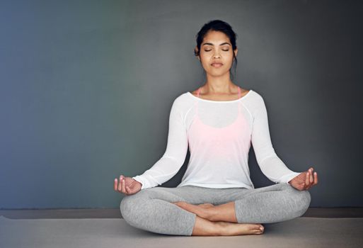 Creating her own calm. an attractive young woman meditating.