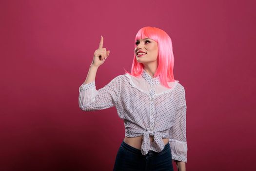 Portrait of beautiful person with pink hair using index finger to point up