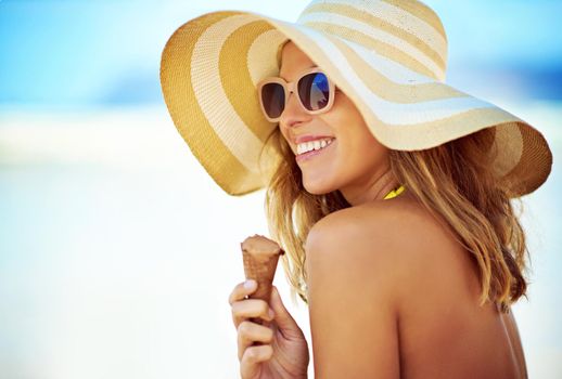 Enjoying an ice cream on the beach. a beautiful young woman eating an ice cream at the beach.