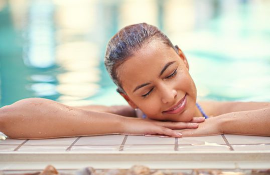 Swim your worries away. a young woman relaxing in the pool at a spa.