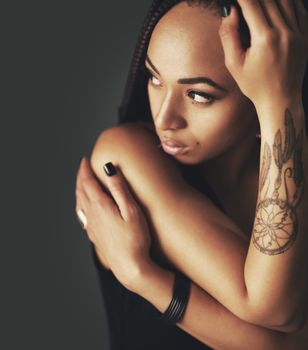To thy own tattoo be true. Studio shot of a beautiful young woman with a tattoo on her arm against a gray background.