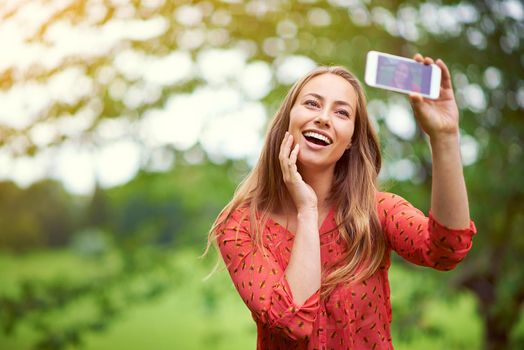 Sunshine and happiness selfie. a young woman taking a selfie outside.